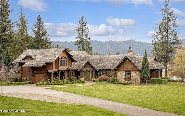 7566 E Gem Shores Rd, Hayden, ID 83835 - view of front of house with a garage, a front yard, stone siding, a chimney, and a mountain view