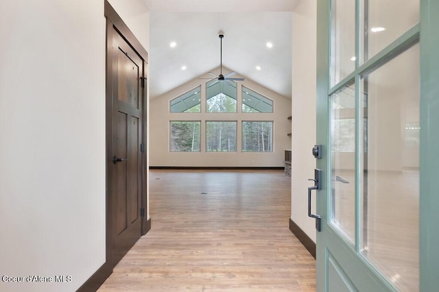 hall featuring baseboards, light wood-style flooring, and lofted ceiling