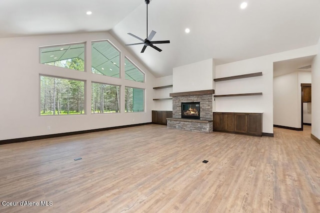 unfurnished living room featuring baseboards, ceiling fan, a fireplace, and light wood-style flooring