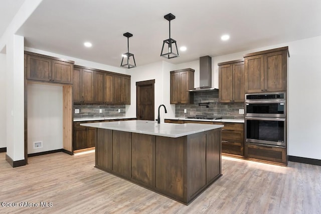 kitchen featuring double oven, wall chimney range hood, light countertops, gas stovetop, and tasteful backsplash