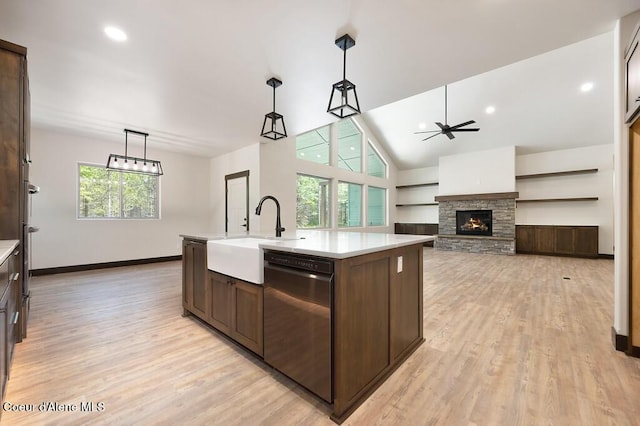 kitchen featuring dark brown cabinetry, stainless steel dishwasher, a sink, light countertops, and light wood-style floors