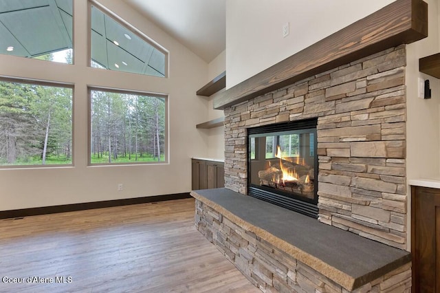 living room with light wood-style floors, baseboards, a fireplace, and vaulted ceiling