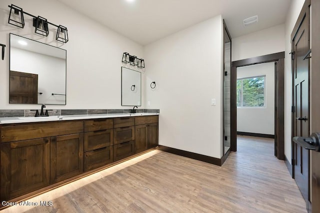 full bath featuring double vanity, baseboards, a sink, and wood finished floors
