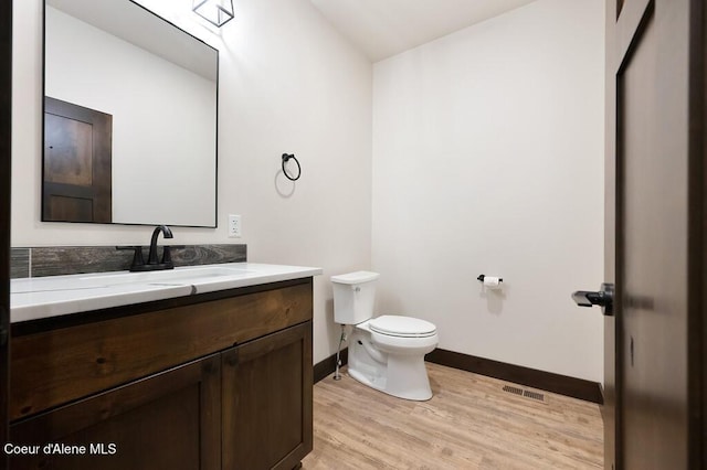 bathroom featuring visible vents, vanity, wood finished floors, toilet, and baseboards