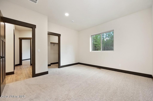 unfurnished bedroom featuring a closet, visible vents, light carpet, baseboards, and recessed lighting