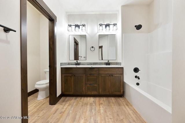 bathroom featuring double vanity, a sink, wood finished floors, and toilet