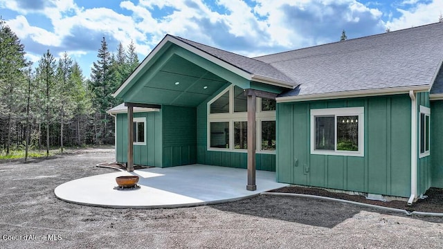 rear view of property featuring a patio, board and batten siding, and roof with shingles
