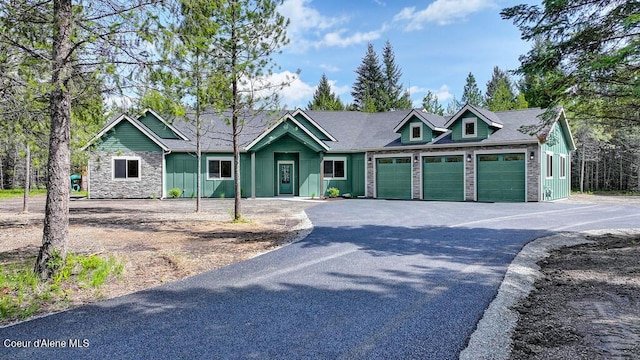 view of front of home featuring board and batten siding, an attached garage, driveway, and stone siding