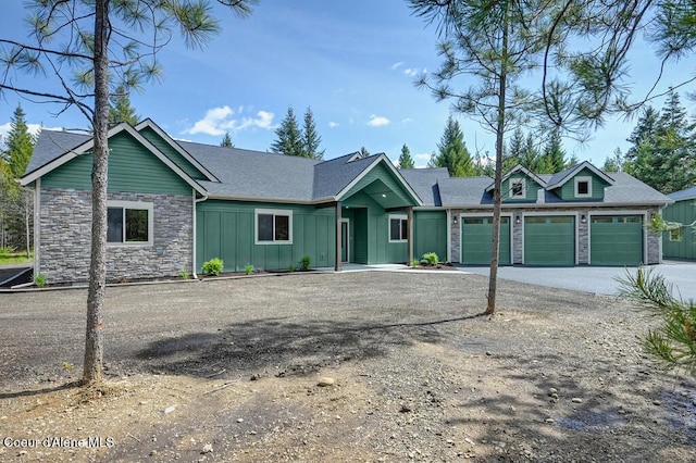 view of front of property with an attached garage, board and batten siding, driveway, and stone siding