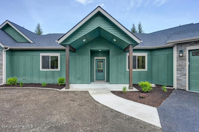 view of front facade with board and batten siding and roof with shingles