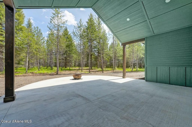 view of patio featuring a view of trees and a fire pit
