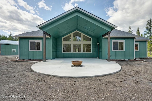 back of house with board and batten siding, a patio, and a fire pit