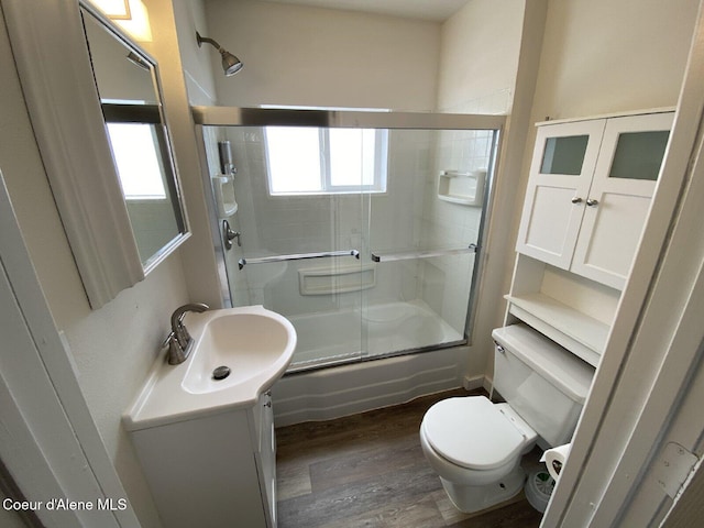 bathroom featuring vanity, combined bath / shower with glass door, toilet, and wood finished floors