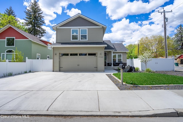 view of front of property with fence, an attached garage, concrete driveway, and a front lawn