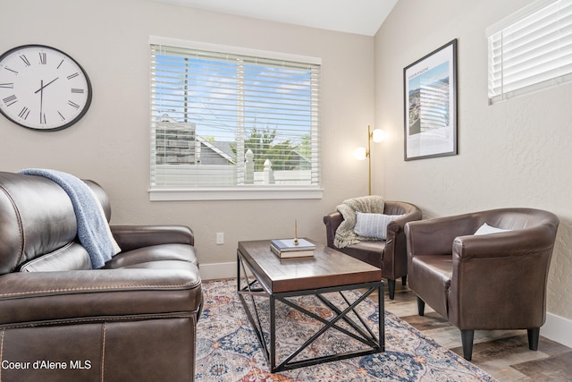 living area featuring baseboards, lofted ceiling, and wood finished floors