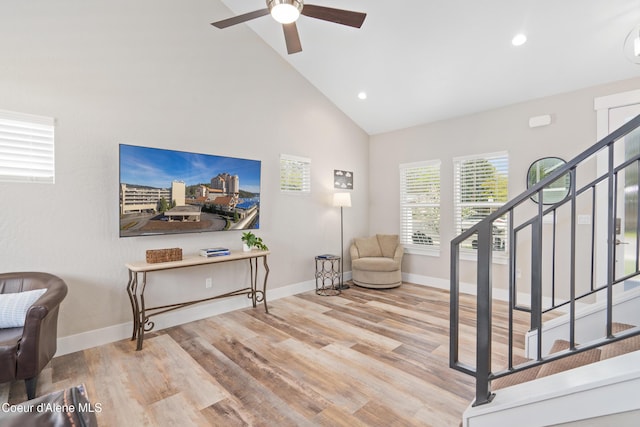 living area with baseboards, a ceiling fan, stairs, and wood finished floors