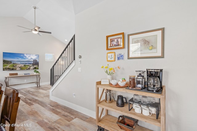 stairs with baseboards, a ceiling fan, high vaulted ceiling, and wood finished floors