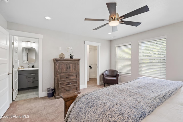 bedroom featuring light carpet, a sink, recessed lighting, baseboards, and ensuite bathroom