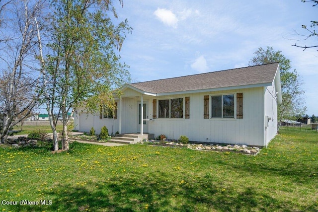 ranch-style home featuring a shingled roof and a front lawn
