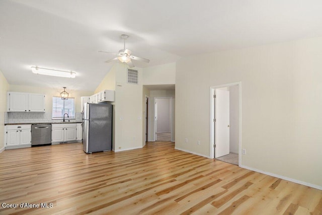 unfurnished living room with a sink, lofted ceiling, light wood-style flooring, and visible vents