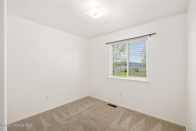 carpeted empty room featuring baseboards and visible vents