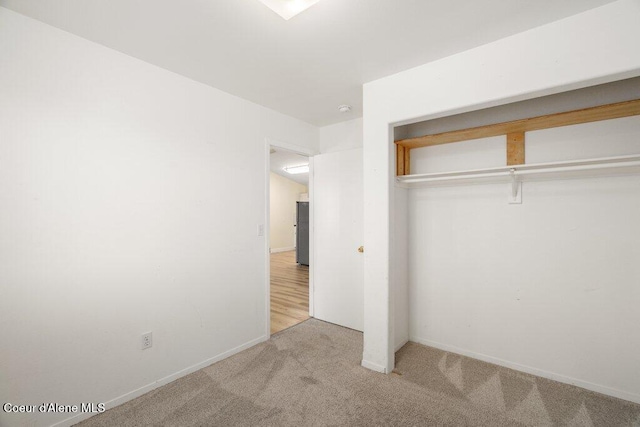 unfurnished bedroom featuring a closet, baseboards, and carpet flooring