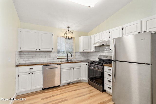 kitchen with a sink, appliances with stainless steel finishes, under cabinet range hood, and dark countertops