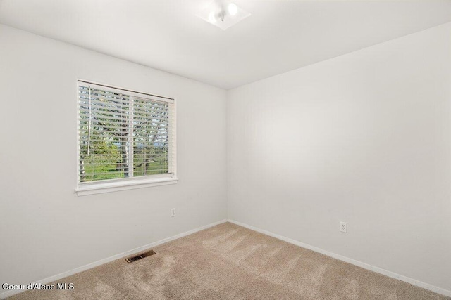 carpeted spare room featuring baseboards and visible vents