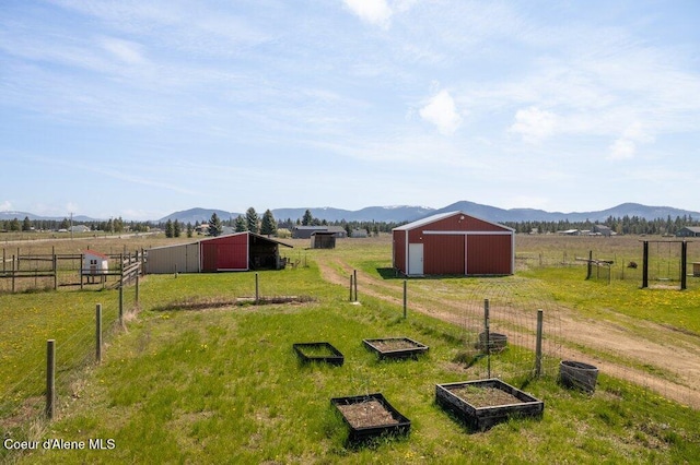view of yard with a mountain view, fence, an outbuilding, and a rural view