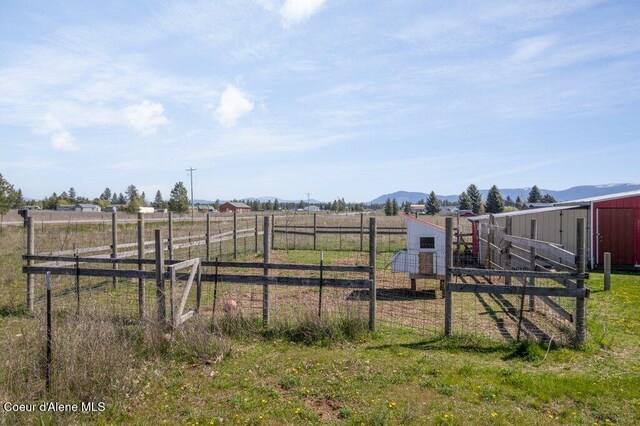 view of yard with fence, an outbuilding, a mountain view, and a rural view
