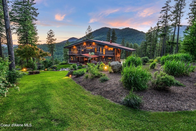 172 Elk Hills Rd, Sandpoint, ID 83864 - back of property at dusk with a deck with mountain view, a lawn, and a chimney