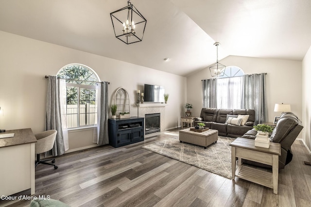 living area with a fireplace, lofted ceiling, wood finished floors, and a notable chandelier