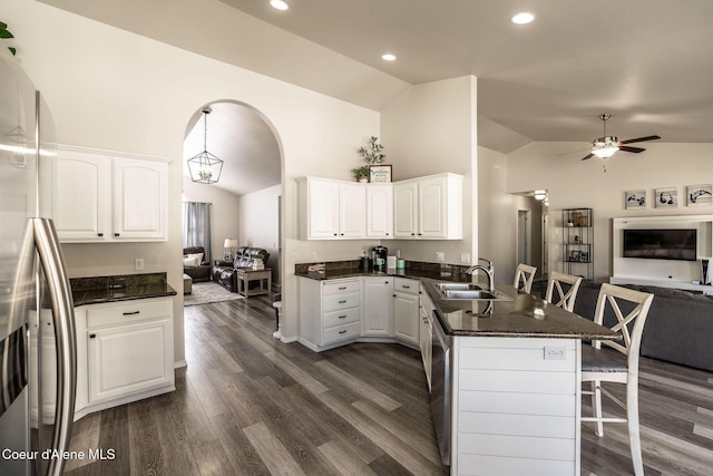 kitchen featuring a peninsula, open floor plan, a kitchen breakfast bar, a sink, and appliances with stainless steel finishes