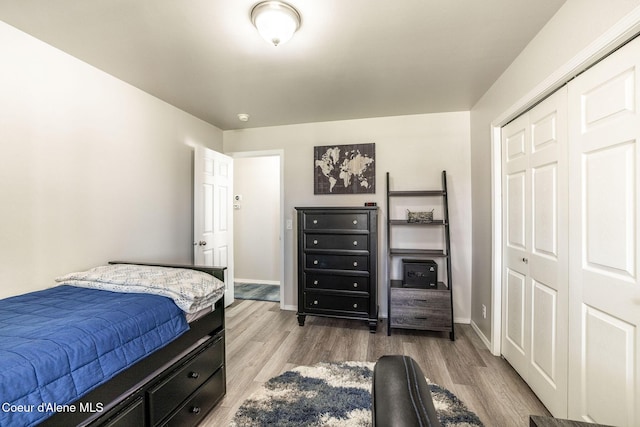 bedroom with baseboards, wood finished floors, and a closet