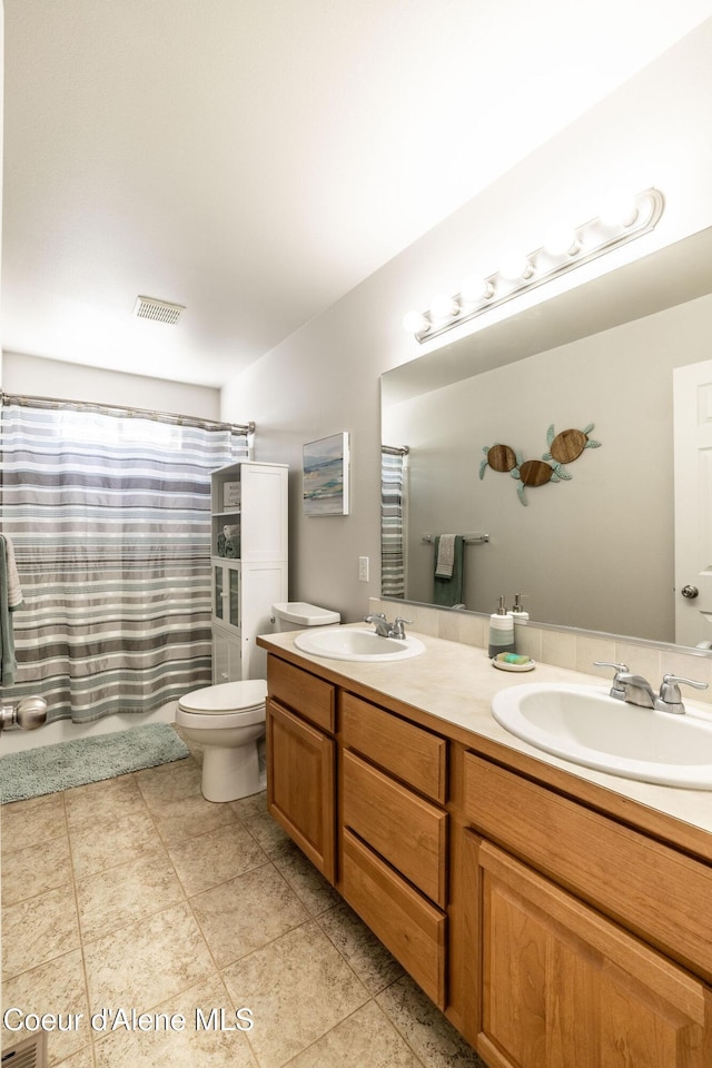 bathroom with double vanity, a sink, and toilet