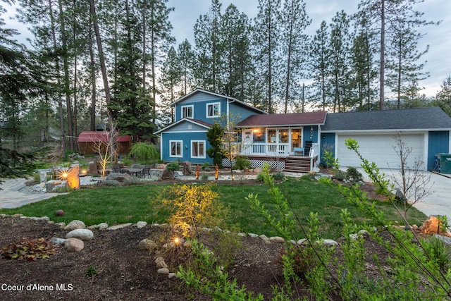 rear view of house featuring a garage, a yard, a porch, and driveway