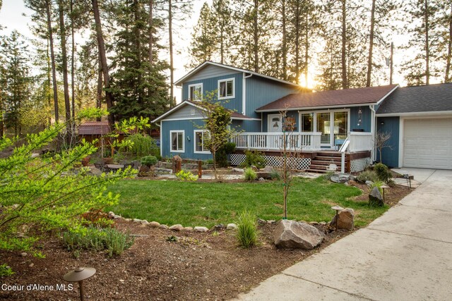 view of front of home with driveway, a wooden deck, a front yard, and a garage