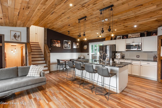 kitchen featuring a kitchen bar, white cabinetry, wooden ceiling, light wood finished floors, and appliances with stainless steel finishes