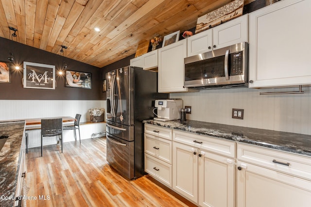 kitchen with appliances with stainless steel finishes, wooden ceiling, white cabinets, light wood-style floors, and dark stone counters