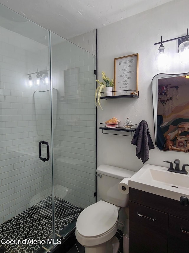bathroom with toilet, a shower stall, and vanity