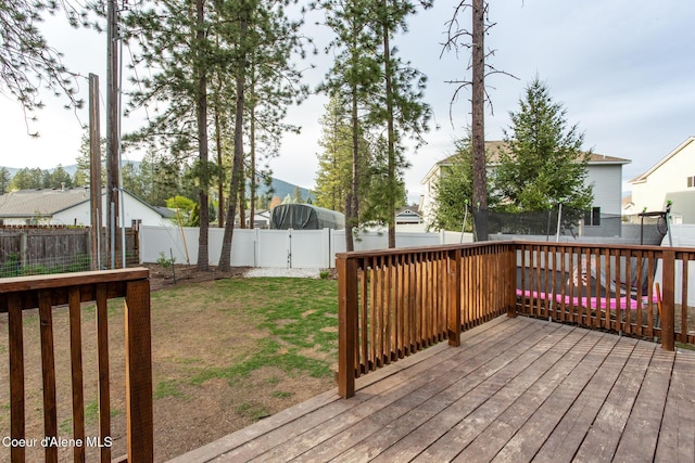 deck with a lawn, a fenced backyard, and a trampoline