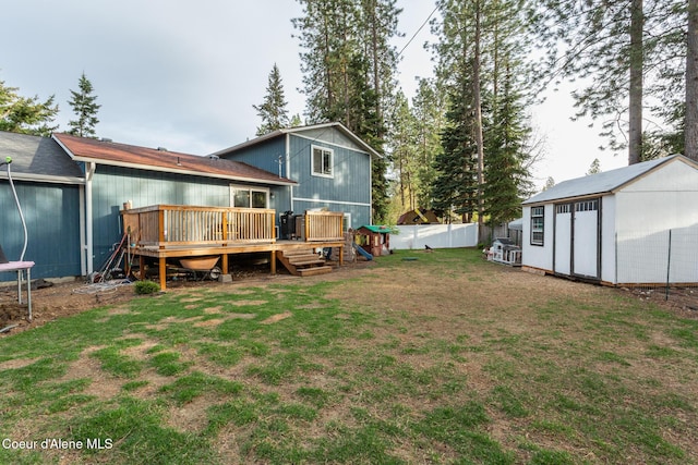 rear view of house featuring an outdoor structure, fence, a deck, a storage shed, and a yard