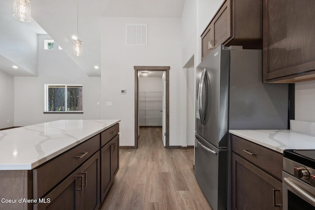 24903 N Old Highway 95, Athol, ID 83801 - kitchen featuring high vaulted ceiling, light wood finished floors, dark brown cabinets, hanging light fixtures, and light stone counters