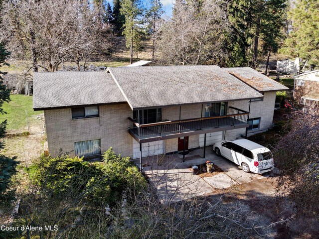 13604/06 E Nora Ave, Spokane Valley, WA 99216 - exterior space with roof with shingles, brick siding, a balcony, concrete driveway, and an attached garage