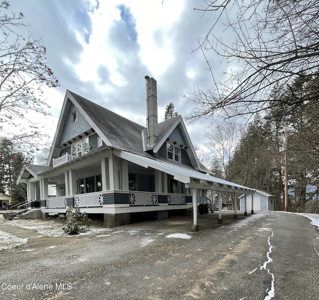 6990 Denver St, Bonners Ferry, ID 83805 - view of home's exterior with roof with shingles, covered porch, an outdoor structure, and a chimney