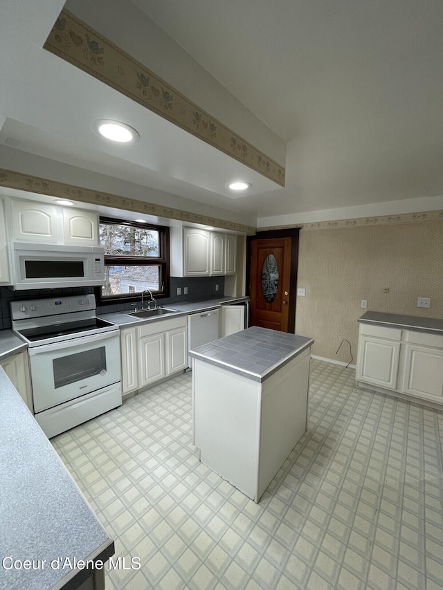 6990 Denver St, Bonners Ferry, ID 83805 - kitchen featuring white appliances, wallpapered walls, a center island, white cabinets, and a sink