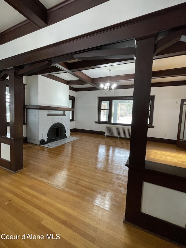 6990 Denver St, Bonners Ferry, ID 83805 - unfurnished living room featuring wood finished floors, baseboards, beam ceiling, and a chandelier