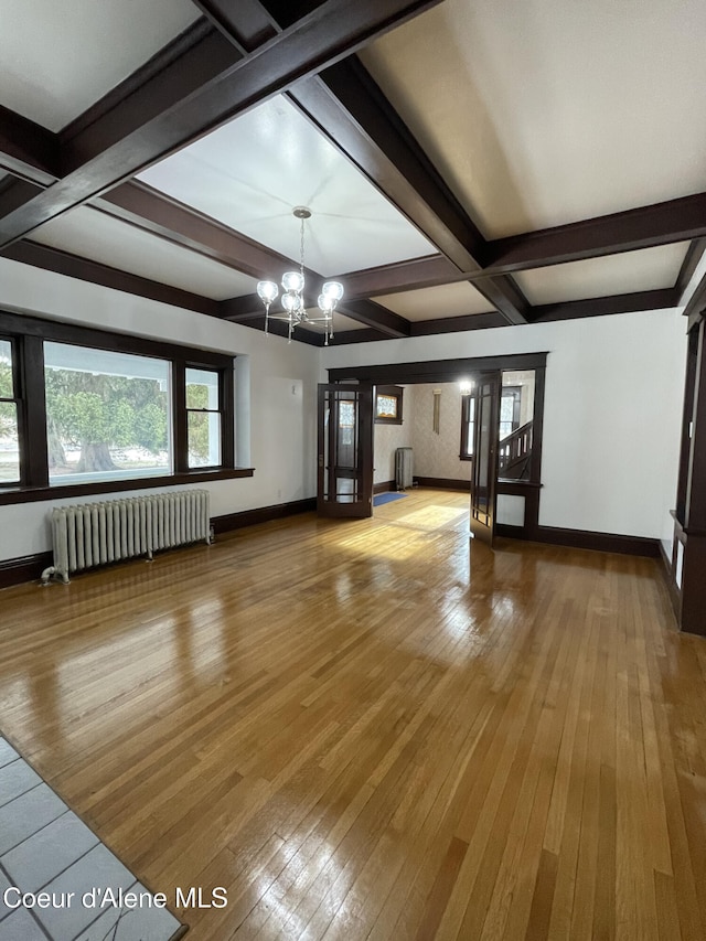 6990 Denver St, Bonners Ferry, ID 83805 - unfurnished living room with an inviting chandelier, radiator, hardwood / wood-style floors, beamed ceiling, and baseboards