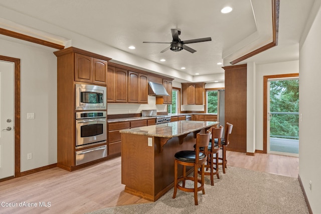 1358 S Starlight Dr, Coeur Dalene, ID 83814 - kitchen with light stone countertops, wall chimney range hood, brown cabinets, a warming drawer, and stainless steel appliances