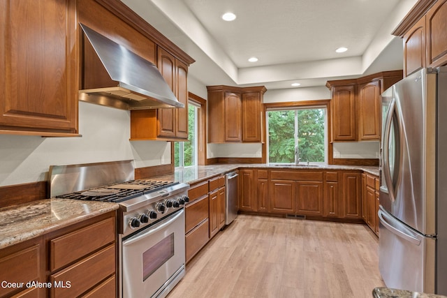 1358 S Starlight Dr, Coeur Dalene, ID 83814 - kitchen with light wood-style floors, wall chimney range hood, brown cabinets, a sink, and stainless steel appliances